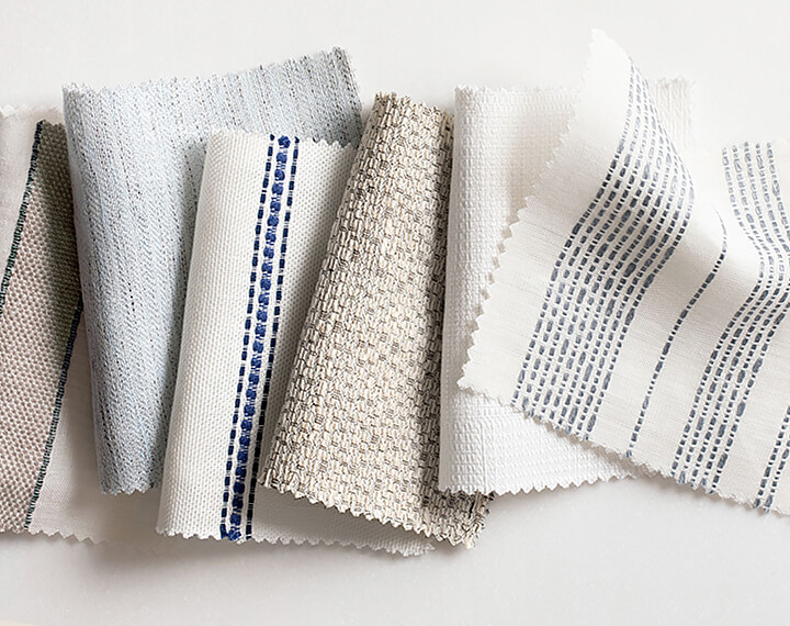 Various light-colored material swatches with stripes on a white table.