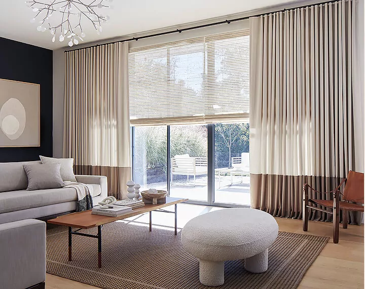 A cozy living room with Woven Wood Shades and tonal Drapery.