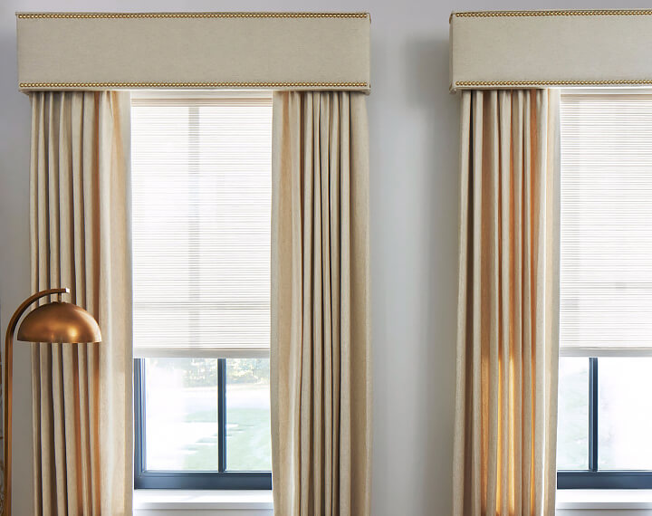 A living room with large windows dressed with Drapery and Cornices with Nailheads.