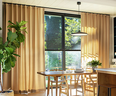 A bright dining room has shades for sliding glass doors under Cubicle Drapery made of Dashing Stripe Palomino