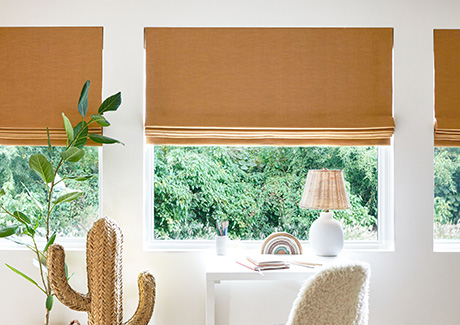 A girls room has a desk and chair by windows with Flat Roman Shades made of Nate Berkus Lisbon Woven in Bronze