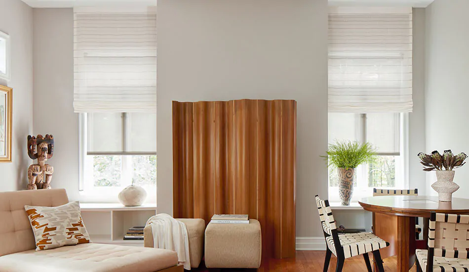 Tall windows in a room with rich wood flooring feature motorized cordless Roman Shades made of Sahara Stripe in Desert