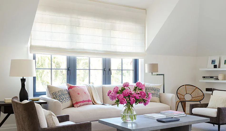 A wide window in a bright sitting room has motorized cordless Roman Shades made of Victoria Hagan's Sankaty Stripe in Moon