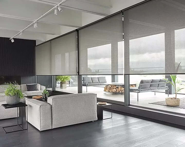 A grey living room with a wall of windows dressed with light filtering 5% Metallic Solar Shades in Zinc.