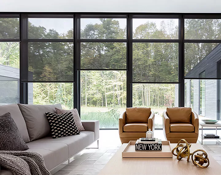 A living room with modern decor and a wall of windows with 10% black Solar Shades.