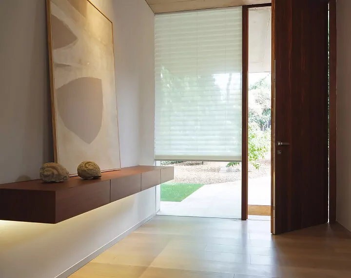 An entry way with a floating shelf and a window with a light filtering Pleated Shade.