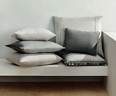 Rectangular pillows in cool grey colors with various trims and fringes show the possibilities for window seat ideas