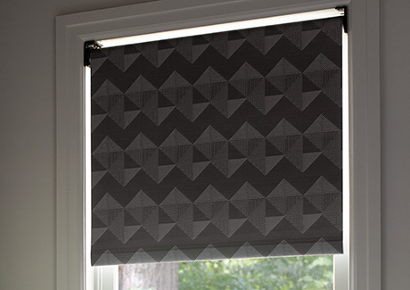 A blackout Roller Shade made of Chilewich Quilt in Tuxedo is inside-mounted on a small bedroom window