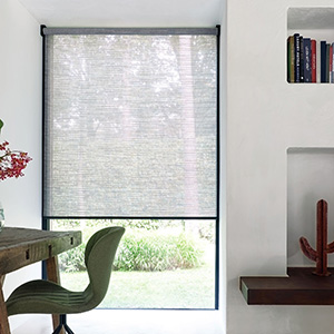 An office features a tall window with a Roller Shade made of Jackson in Grey partially raised