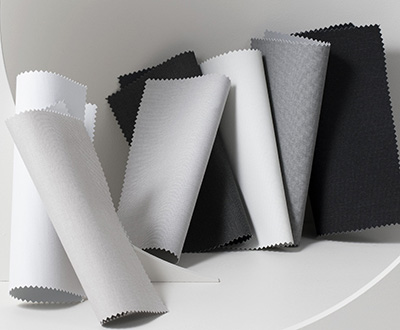 Swatches made of Irving for Roller Shades for windows are folded decoratively on white geometric shapes