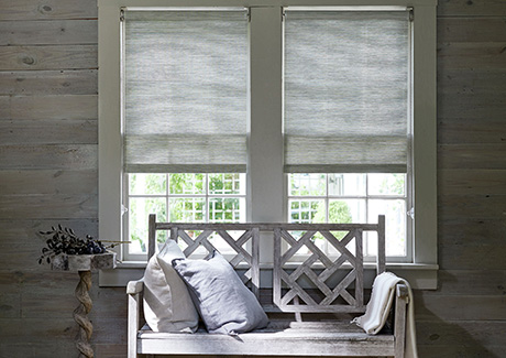 A simple wood bench sits in front of a window with window seat ideas including pillows & Roller Shades in Grassweave, Silver