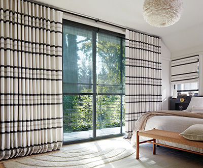 Shades for sliding glass doors are layered under Ripple Fold Drapery made of Shoreham Stripe in Jet