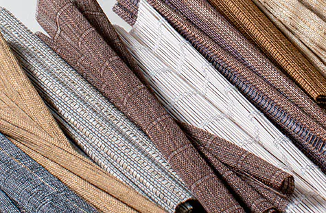 Several swatches of Artisan Weaves woven wood fabric for Roman Shades are folded together to showcase their woven texture