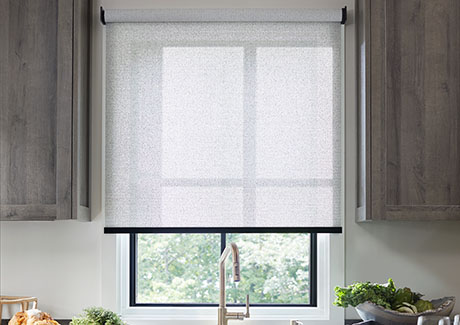 A Solar Shade made of 3% Solistico in Ash is outside-mounted over a kitchen window above the sink and between grey cabinets