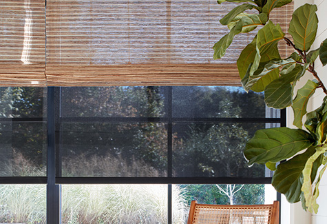 A close up image of shades for sliding glass doors shows layered solar shades under woven wood shades