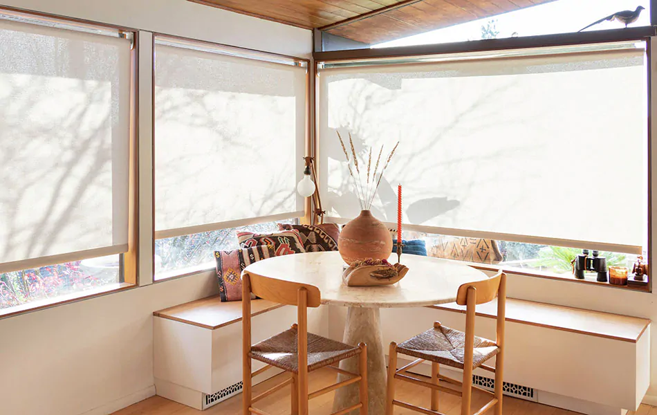 A breakfast nook features window seat ideas including a built-in wood bench and Solar Shades made of 1% Solistico in Oatmeal