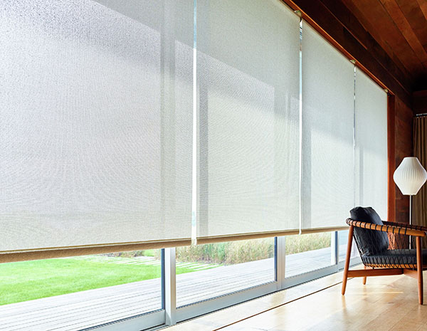 Tall, wide sliding glass doors covered by Solar Shades made of 10% Solistico in Oatmeal let sunlight into a large room