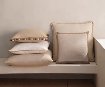 Square pillows in warm tan fabrics with various trims and fringe show the possibilities for window seat ideas
