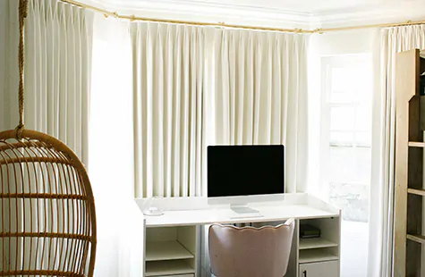 Home office curtains made of Sheer Brilliance in Godl wiht privacy lining provide light control to a bay window office 