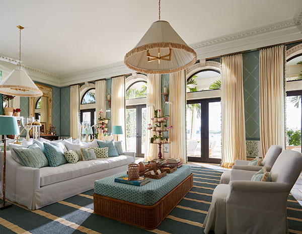 Neutral curtains made of Luxe Linen in Oyster hang over arched windows above glass doors in a luxe room with teal walls