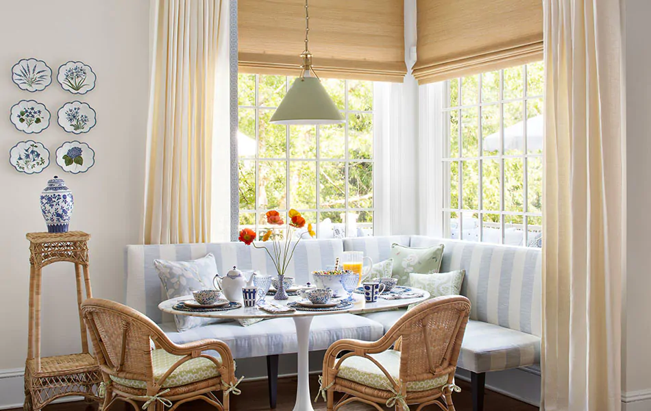 A cottage-inspired corner has window seat ideas like a blue & white bench & Luxe Linen Tailored Pleat Drapes with Woven Shades