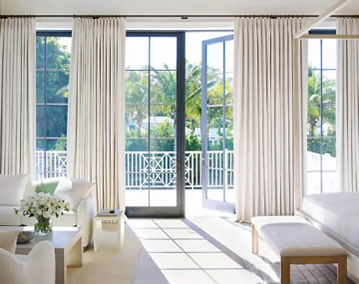 A bright, sunlit bedroom with Tailored Pleat Drapery on patio doors.