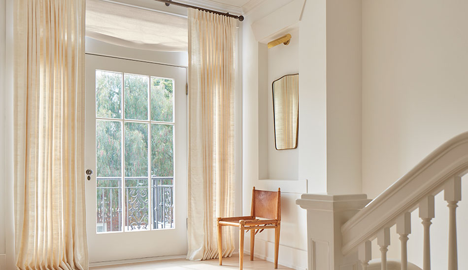 Neutral curtains made of Raw Silk in Glacier elevate a foyer with their natural texture and warm creamy ivory color
