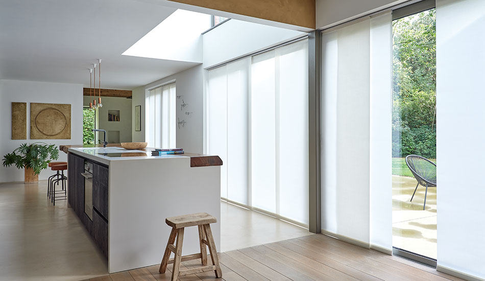 An open concept kitchen with a mid-century modern design has vertical blinds over sliding glass doors