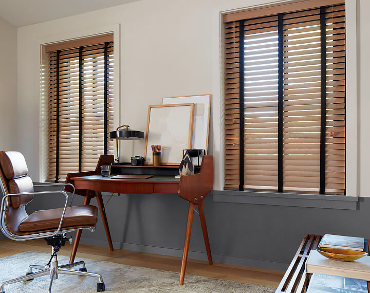 An office with a wooden desk and windows dressed with Oak Wood Blinds.