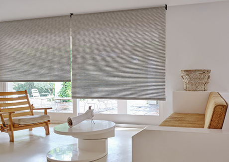 A mid-century modern living room has roller shades for sliding glass doors made of mesa verde in mist