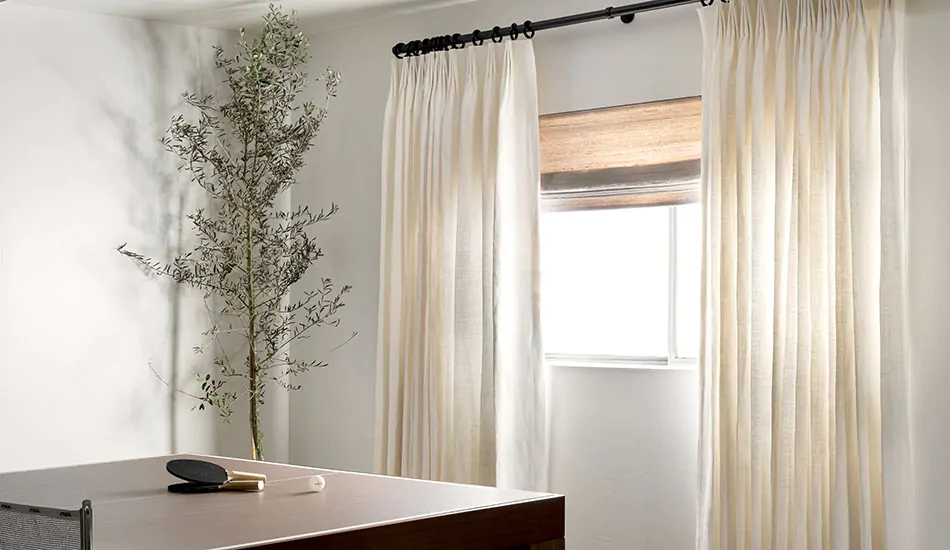 https://www.theshadestore.com/blog/wp-content/uploads/the-shade-store-woven-wood-shade-del-rey-grey-tailored-pleat-drapery-luxe-linen-oyster-basement-window-curtains-rec-content-2022-studio-mcgee-950x550px.jpg.webp